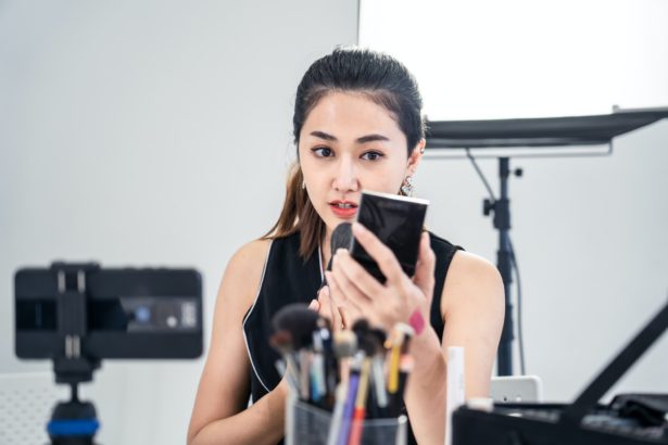 Asian young beauty cosmetic blogger woman record clip video about make up techniques at studio.