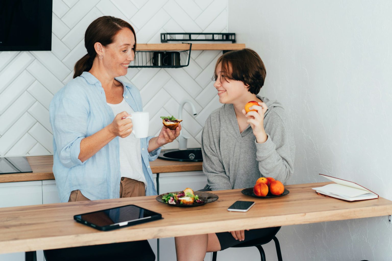 Relationship between a teenager and a parent. Mom and teenage daughter are having breakfast