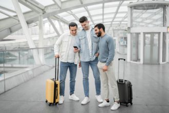Three Tourists Men Using Smartphones Using Travel Application At Airport