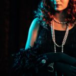 woman standing in old historical 20th century in flapper dress with fringe, feathers boa.