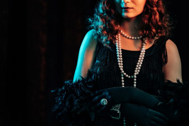 woman standing in old historical 20th century in flapper dress with fringe, feathers boa.