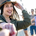 Young brunette woman with blue eyes inviting you to dance in a beach party