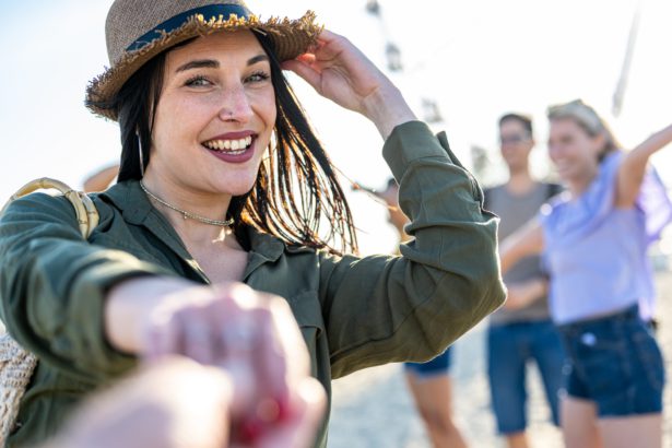 Young brunette woman with blue eyes inviting you to dance in a beach party